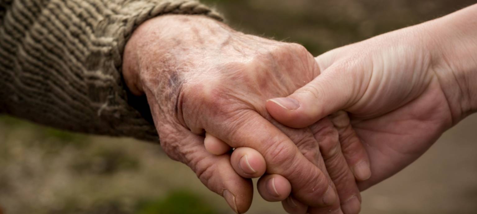 younger hand holding elderly hand